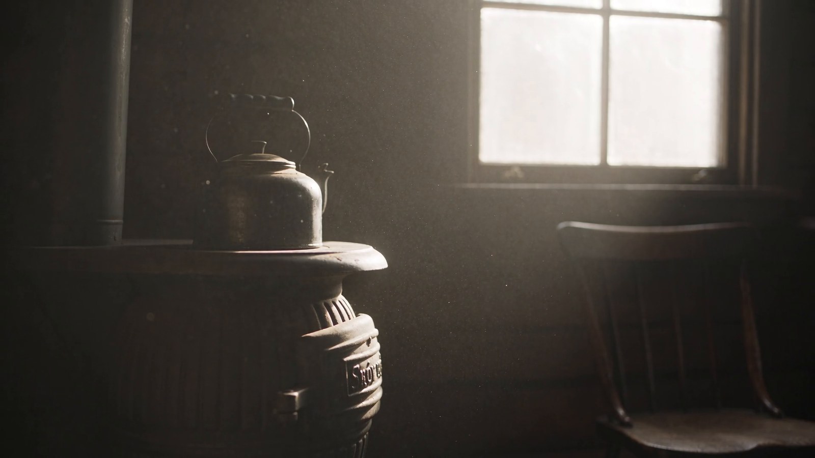 A cold wood stove with a kettle on top in an empty one-room cabin, pale light through a dusty window.