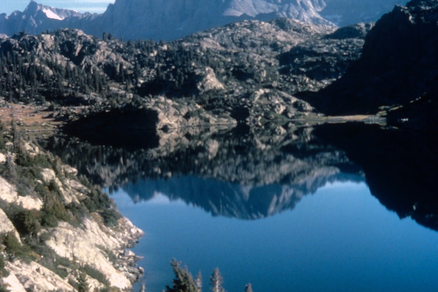 A granite peak of the Wind River Range reflected in a still alpine lake.